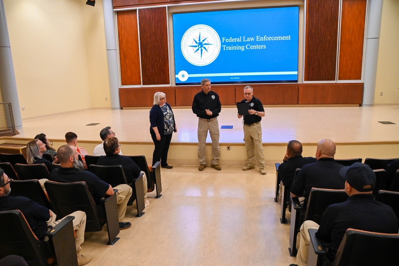 Federal Law Enforcement Training Centers Director Benjamine C. Huffman and Site Director Robert D. Price present Disability Program Manager (Henry Rolon/FLETC OPA)